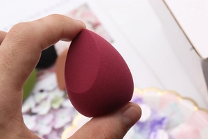 Detail of soft burgundy teardrop makeup sponge with a flat cut edge for precision
