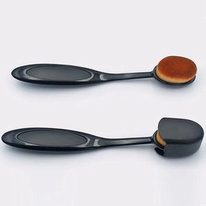 Detail of oval foundation brush with dense synthetic bristles and plastic protective cover