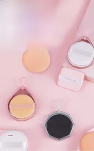 Macro detail of various non-latex makeup sponges in clear storage cases with brand ribbon