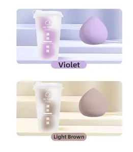 Détail d'éponges maquillage pêche en violet et marron clair avec contenants de tasse