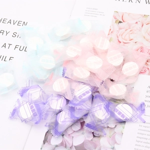 Colorful compressed facial mask tablets in candy packaging on floral background