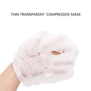 Thin transparent compressed facial mask made of non-woven fabric held by a hand