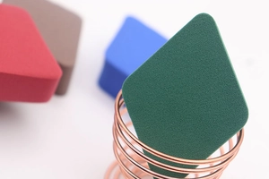 Detail van zachte ruitvormige make-up sponsjes met een roségouden metalen houder