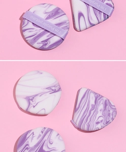 Close-up of marble pattern cushion puffs with purple ribbon handle for makeup