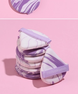 Macro shot of purple marble makeup puffs in triangle and teardrop shapes on pink background