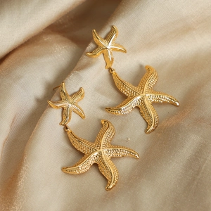 Golden double starfish earrings with textured finish on elegant champagne silk fabric