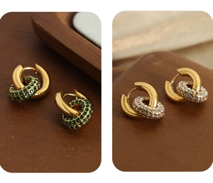 Détail macro de boucles d'oreilles dorées avec cristaux de zircone verts et blancs polis