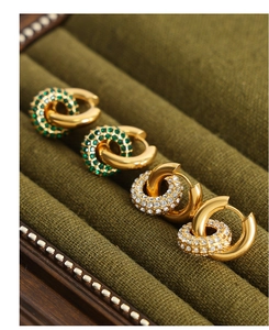 Détail de boucles d'oreilles double cercle dorées avec cristaux émeraude et clairs