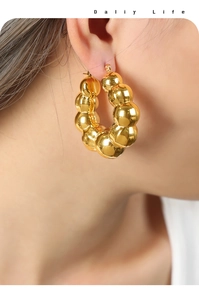 Gros plan détaillé de boucles d'oreilles créoles dorées avec un design à billes polies