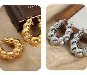Détail de boucles d'oreilles boules en U épaisses avec finitions dorées et argentées