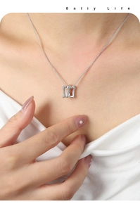 Gros plan sur le pendentif géométrique argenté à double boucle sur collier délicat