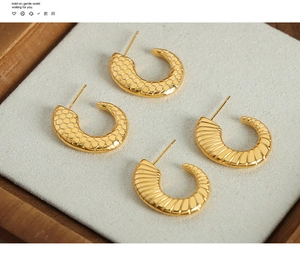 Macro view of C-shaped titanium earrings with honeycomb pattern and striped texture