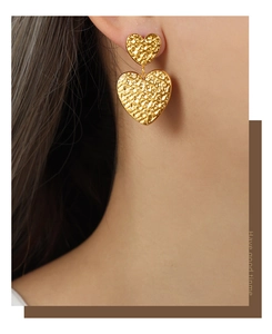 Gros plan sur boucles d'oreilles double cœur à texture martelée en acier titane doré