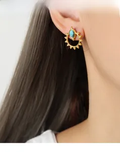 Close-up of bohemian sun-shaped titanium steel earring with turquoise stone inlay