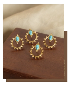 Detailed close-up of retro sun-shaped earrings with inlaid turquoise stones on wood