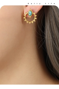 Detail of sunburst titanium steel earring with turquoise stone inlay on model