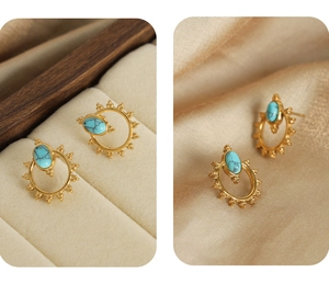 Detail of sun-shaped gold titanium earrings with oval turquoise stone on silk