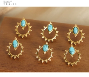 Detail of bohemian sunburst gold earrings with oval turquoise stones on a wood surface