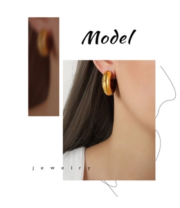 Detailed close-up of chunky gold-plated C-shaped hoop earrings worn by a female model