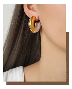 Detail view of two-tone C-shaped thick hoop earrings in 18k gold plating and white enamel