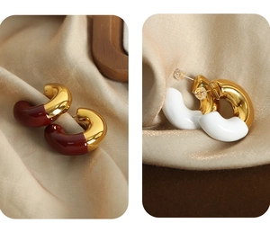 Detail of U-shaped gold-plated earrings with burgundy and white enamel on champagne silk