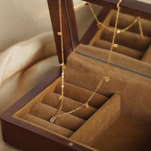 Collar de acero de titanio dorado con colgantes de circón en un joyero de madera