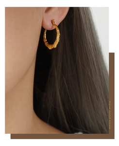 Close-up of bamboo-style 18k gold plated hoop earrings worn on female ear