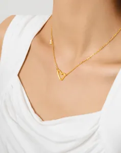 Primo piano di una collana dorata con ciondolo a cuore vuoto e zircone su una modella