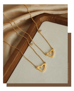 Dettaglio della collana con ciondolo a cuore dorato e zircone su seta e legno
