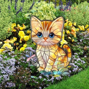 Close-up of a decorative cat garden stake with orange mosaic pattern in a flower bed
