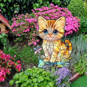 Detail of cute orange cat garden stake with colorful mosaic pattern among flowers