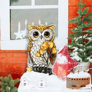 Outdoor winter scene featuring a cartoon owl garden stake with colorful floral patterns