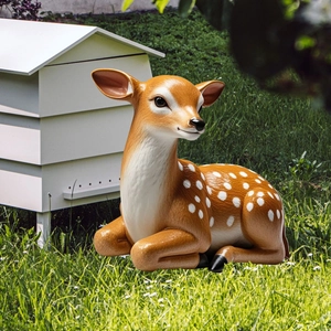 Realistic spotted deer garden ornament resting on grass with a white wooden beehive prop