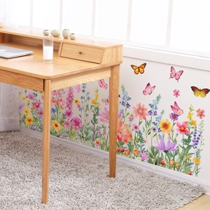 Detail of colorful floral and butterfly wall decals on a white wall above a wooden desk