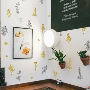 Detail of floral wall stickers with golden and black leaf designs on white wall