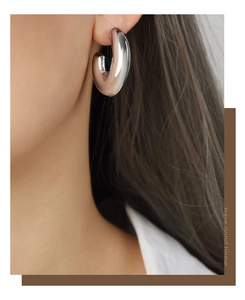 Nahaufnahme von polierten silbernen C-Form Creolen für einen eleganten minimalistischen Look