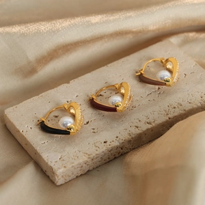 Elegant gold heart earrings with pearl and crystal inlay on champagne satin background