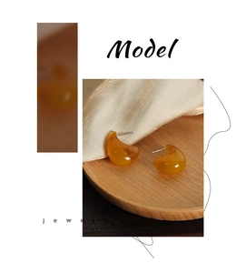 Detail of bohemian amber resin teardrop earrings on elegant silk and wood tray