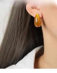 Close-up of amber resin teardrop earrings with high polish on female model