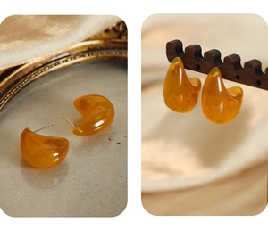 Macro detail of amber resin teardrop earrings on vintage gold frame and silk