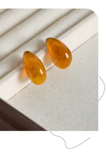 Macro shot of amber resin teardrop earrings with gold plating and marble texture