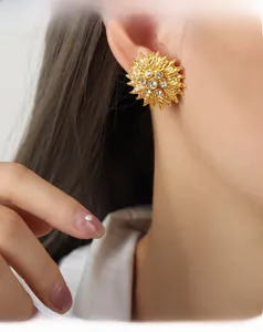 Close-up of a golden sunflower earring with sparkling zircon petals on a model