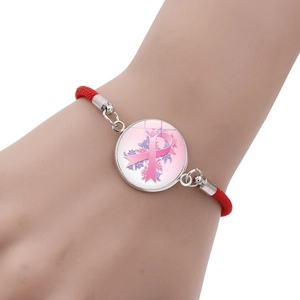 Pink ribbon breast cancer awareness bracelet with red woven rope on female wrist