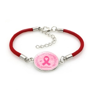 Close-up of pink ribbon breast cancer awareness charm on a red braided rope bracelet