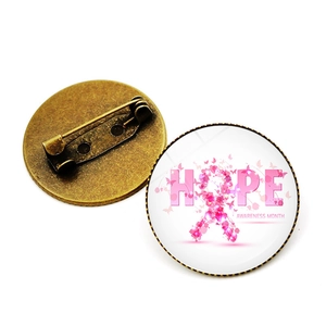 Detailed view showing both sides of a pink ribbon hope brooch with metal safety pin back