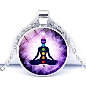 Détail d'un pendentif de méditation argenté avec sept symboles chakra et motif lotus