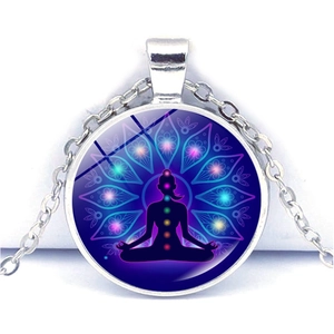 Détail macro du pendentif yoga argenté avec sept chakras et insert en verre mandala