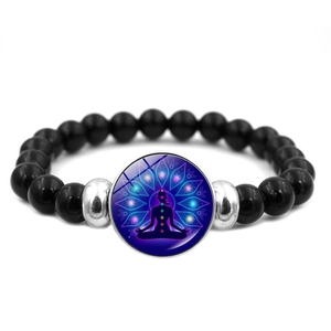 Macro detail of yoga meditation charm on black beaded chakra balancing bracelet