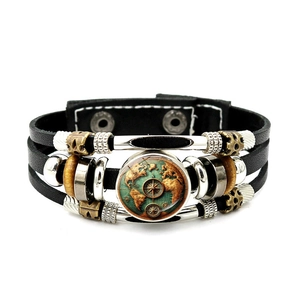 Detailansicht eines nautischen Kompasses und einer Weltkarte auf einem mehrlagigen Lederarmband