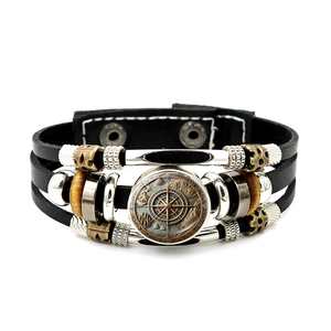 Detail eines Vintage-Punk-Lederarmbands mit Kompass-Glasanhänger und mehrlagigen Perlen